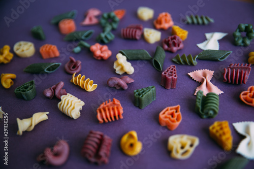 Multicolored pasta shapes on colorful background. 