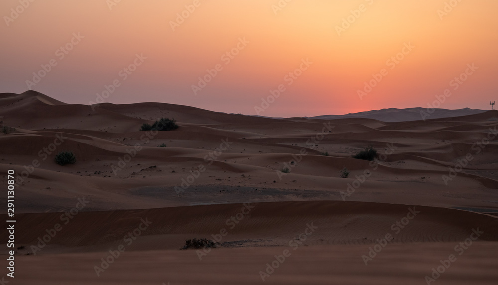 Sunset in the desert in UAE. Sun is setting behind the sand dunes. Sunset in the desert in UAE. Sun is setting behind the sand dunes.