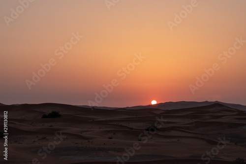 Sunset in the desert in UAE. Sun is setting behind the sand dunes.