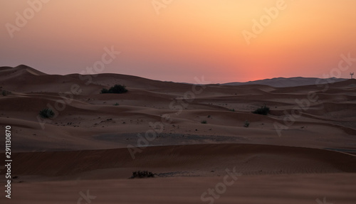 Sunset in the desert in UAE. Sun is setting behind the sand dunes.