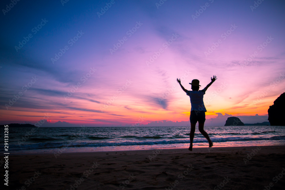 Silhouette of The girl is walking happily Use the phone at the beach during the sunset and her enjoying freedom feeling happy at sunset 