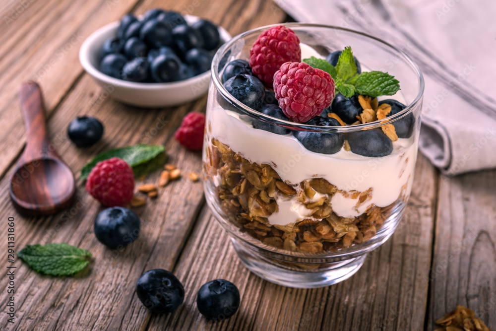 granola with yogurt and fresh blueberries in a glass on wooden background granola with yogurt and fresh blueberries in a glass on wooden background