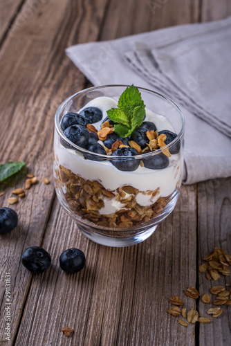 granola with yogurt and fresh blueberries in a glass  on wooden background