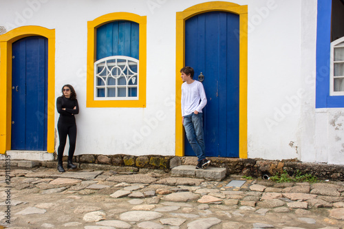 Teenage girl and boy exchange glances and charms on an old cobblestone street. © Rogerio