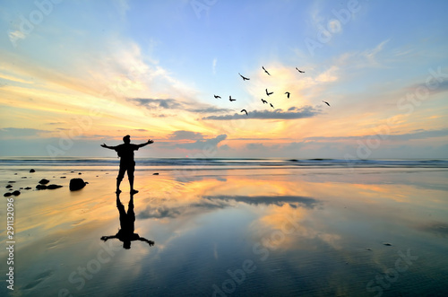 Man standing near the beach looking at sun rising