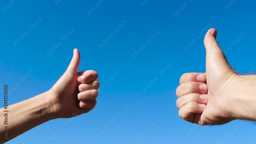 Hand gestures close-up. Male and female hands thumbs up against the blue sky, OK, good, great. Hand gestures close-up. Male and female hands thumbs up against the blue sky, OK, good, great.