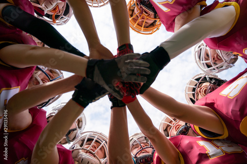 Image of female rugby players stacking their hands together