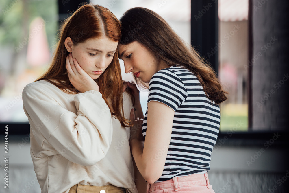 Naklejka premium two sad friends in casual outfits looking down