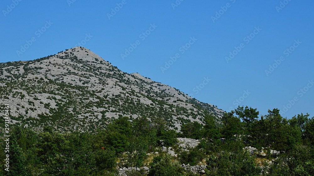 Rocky hill of Velebit mountain with some vegetation during hot summer day. Location near Paklenica national park, Croatia, 