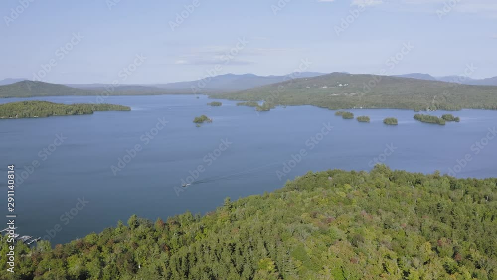 Wide shot of a lone boat on Sunny day on a large lake in early fall AERIAL PUSH IN Wide shot of a lone boat on Sunny day on a large lake in early fall AERIAL PUSH IN