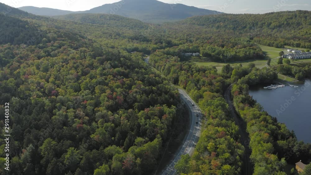 Three cars drive along a curvy road though early fall foliage AERIAL TRACKING Three cars drive along a curvy road though early fall foliage AERIAL TRACKING