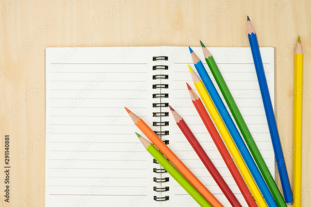 colorful pencils and notebook on wooden background top view. art equipment. colorful pencils and notebook on wooden background top view. art equipment.
