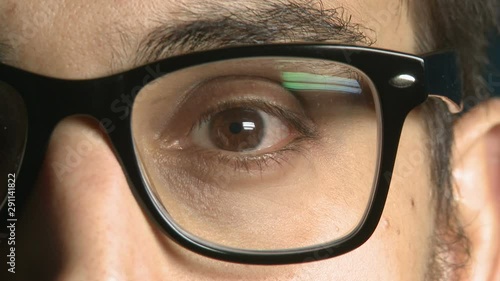 Anonimous young man putting on glasses with black frame one eye close up