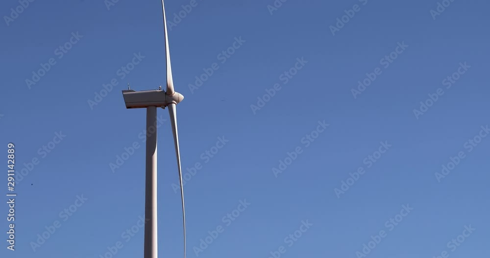 Alternative energy sources. Large blades of wind turbines in rotation with the blue sky in the background - aerial view with a drone - environment & ecological concept Alternative energy sources. Large blades of wind turbines in rotation with the blue sky in the background - aerial view with a drone - environment & ecological concept