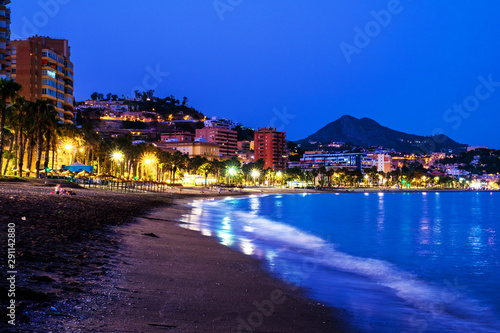 Famous Malagueta beach in Malaga, Spain at night. Coastline and motion blurred waves at sunset