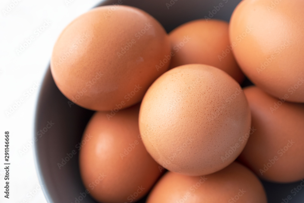 Close-up natural brown organic eggs, top view. Fresh raw chicken eggs in gray bowl, farm product