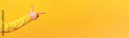 Woman's hand points a finger at something, over yellow background, panoramic mock up image