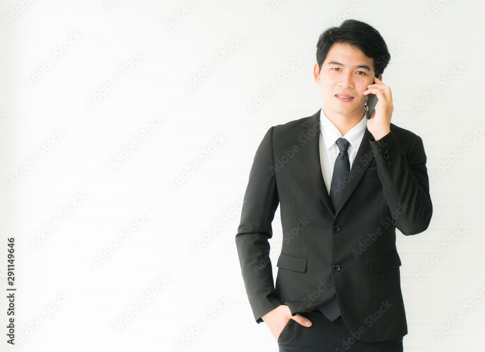 Asian young handsome Business man talking on the mobile phones standing and one hand is in the pant pocket Isolated on white background with copy space Asian young handsome Business man talking on the mobile phones standing and one hand is in the pant pocket Isolated on white background with copy space