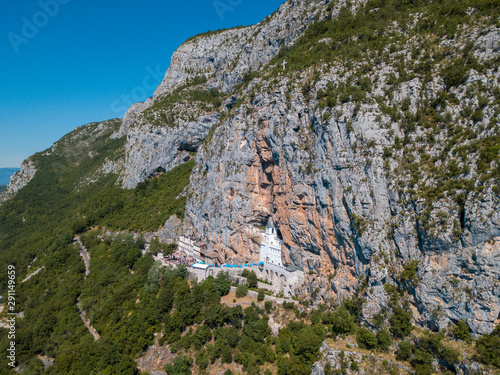 Aerial view of The Monastery of Ostrog, Serbian Orthodox Church situated against a vertical background, high up in the large rock of Ostroška Greda, Montenegro. Dedicated to Saint Basil of Ostrog  photo