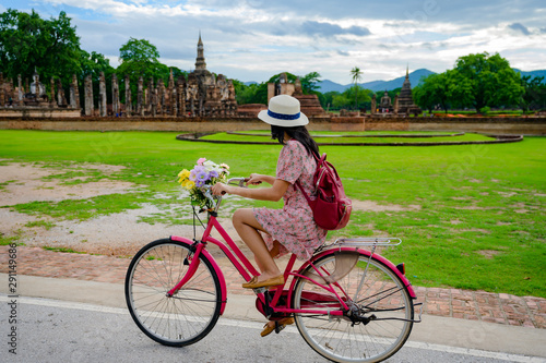 woman tourist enjoy riding vintage bicycle to see the historic park of Thailand, exciting to explore the wonderful place of sightseeing