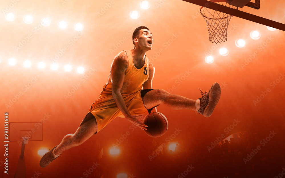 Basketball player in action on a red floodlit sports arena. Slam dunk.