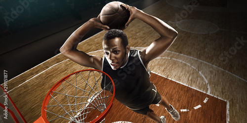 Basketball player makes slam dunk. High angle view from the basketball rim 