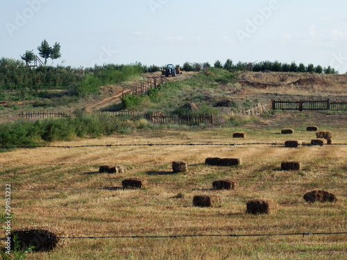 Tractor works on a field with hay