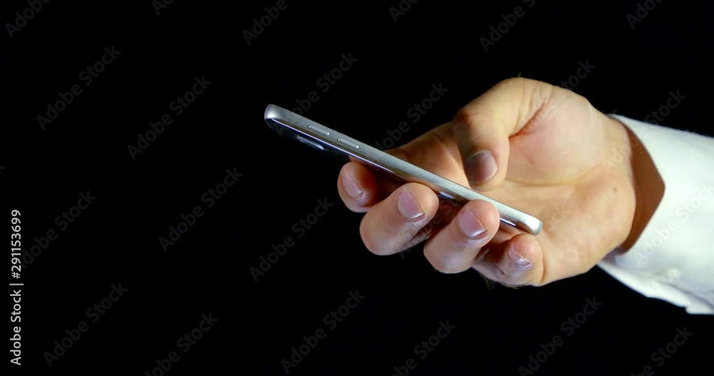 Close-up on a black background a man's hand with a mobile phone access to the Internet Close-up on a black background a man's hand with a mobile phone access to the Internet