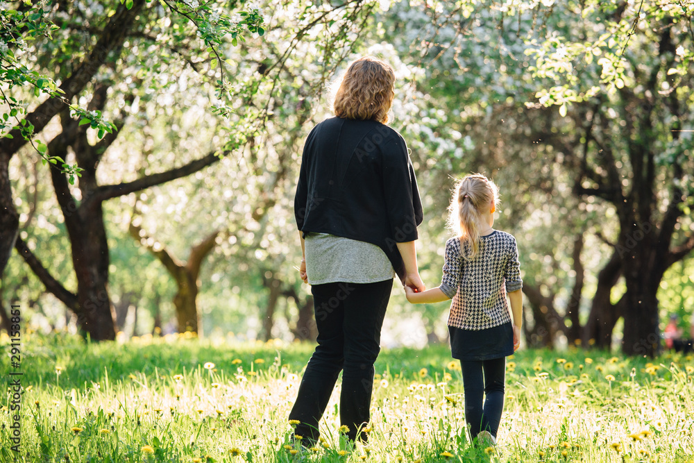 Fototapeta premium Mother and daughter having fun in the park. Happiness and harmony in family life. Beauty nature scene with family outdoor lifestyle. Woman and cheerful little girl