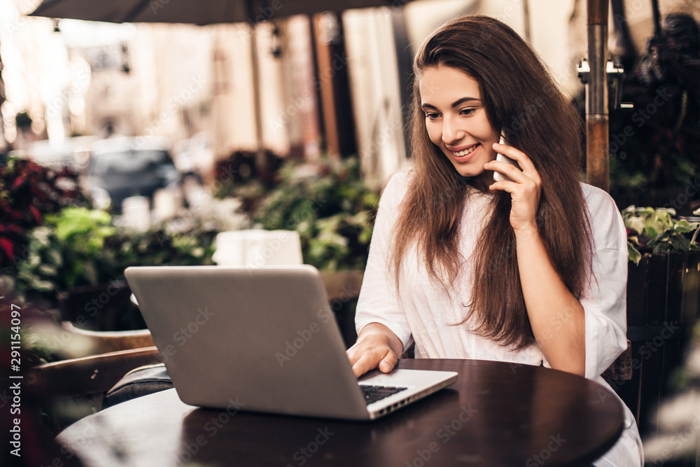 Beautiful woman work on laptop and using phone sitting in street cafe. Beautiful woman work on laptop and using phone sitting in street cafe.