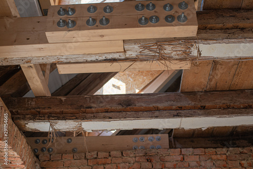 in laborious work an old house is restored, whereby old beams are strengthened with new ones photo
