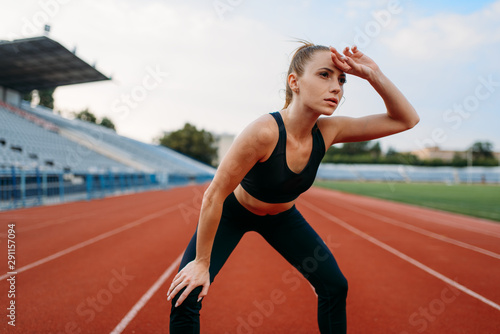 Tired female jogger, training on stadium