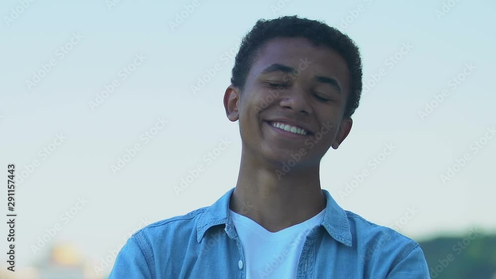 Happy African-American teenager boy smiling at camera outdoors, positivity Happy African-American teenager boy smiling at camera outdoors, positivity