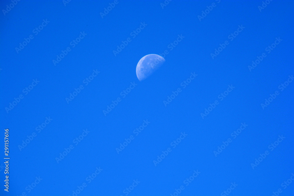 Half Moon During Day in clear Blue Sky, waning moon at daytime azure sky background with copy space Half Moon During Day in clear Blue Sky, waning moon at daytime azure sky background with copy space