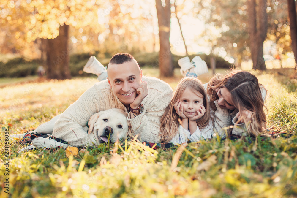 Happy family is having fun with dog labrador are lying on green grass in park. Happy family is having fun with dog labrador are lying on green grass in park.