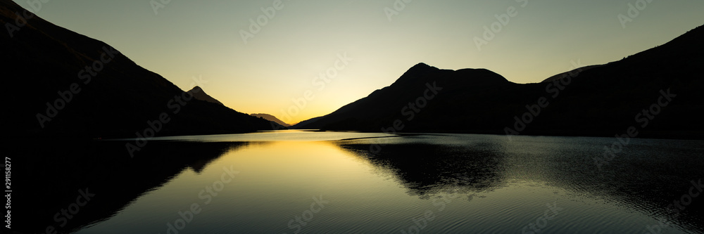 sunset on a clear calm day over loch leven near kinlochleven in the argyll region of scotland during autumn showing calm waters and golden hues