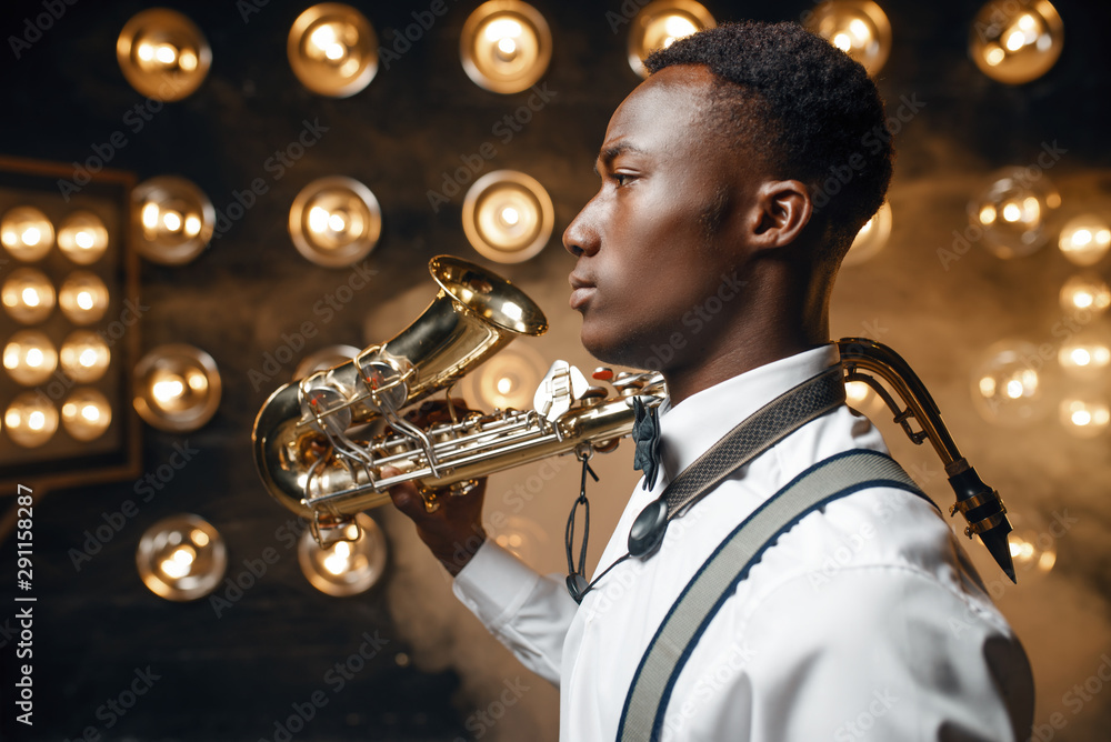 Obraz premium Black jazz performer poses with saxophone on stage