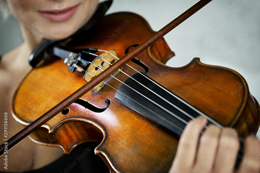 Violin and a fiddlestick close up in hands of a young female violinist during music performance Violin and a fiddlestick close up in hands of a young female violinist during music performance