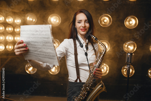 Wall Mural Female saxophonist with saxophone holds music book