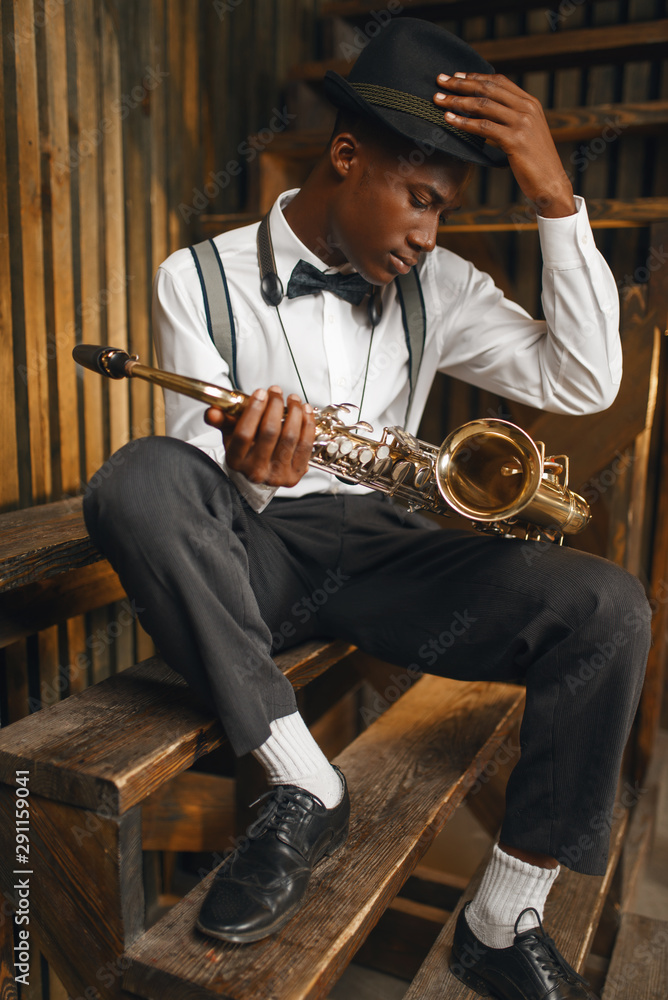 Naklejka premium Black jazz musician sitting with saxophone