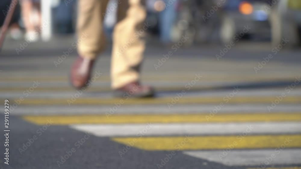 unfocused view of elderly man walking with a cane through a pedestrian crossing unfocused view of elderly man walking with a cane through a pedestrian crossing