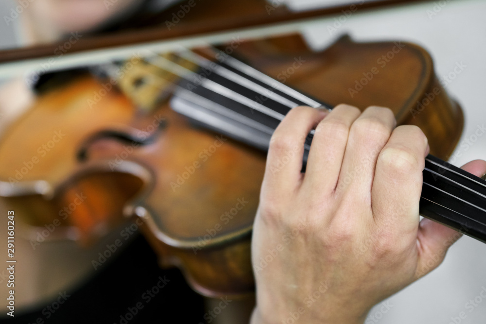 Hand of a female violinist on the fingerboard of a violin close up Hand of a female violinist on the fingerboard of a violin close up