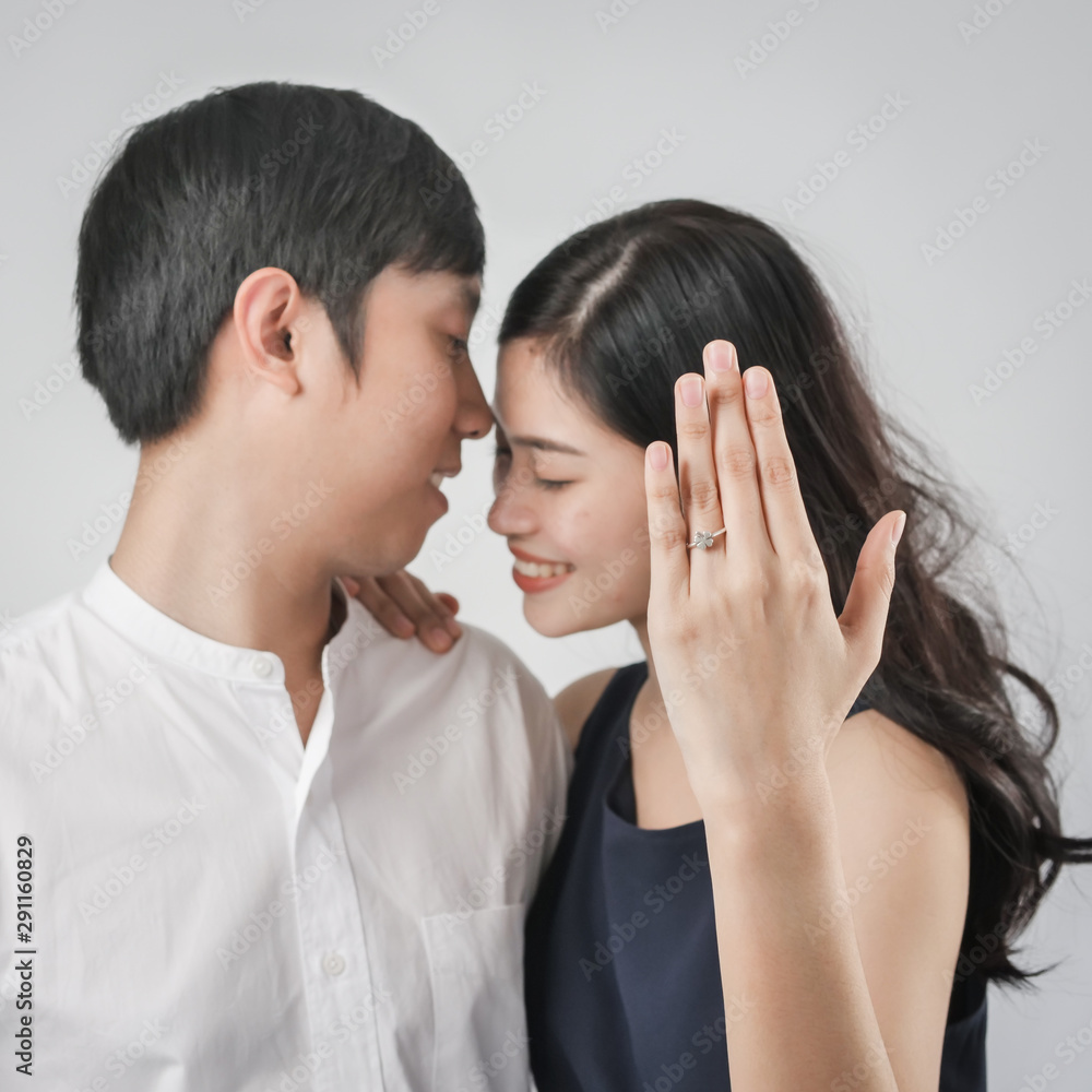 Happy woman showing engagement ring after proposal while is cuddling her boyfriend. Happy woman showing engagement ring after proposal while is cuddling her boyfriend.