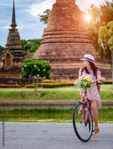 woman tourist enjoy riding vintage bicycle to see the historic park of Thailand, exciting to explore the wonderful place of sightseeing