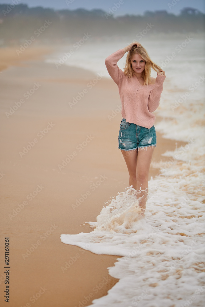 Naklejka premium A beautiful girl walks along the beach and rejoices