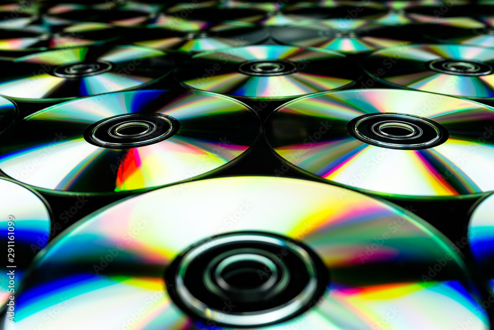 CDs / DVDs lying on a black background with colorful reflections of light. CDs / DVDs lying on a black background with colorful reflections of light.