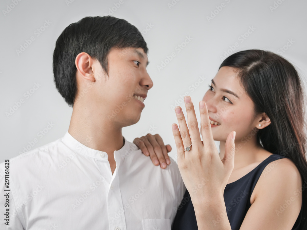 Happy woman showing engagement ring after proposal while is cuddling her boyfriend. Happy woman showing engagement ring after proposal while is cuddling her boyfriend.