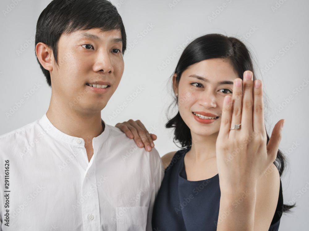 Happy woman showing engagement ring after proposal while is cuddling her boyfriend. Happy woman showing engagement ring after proposal while is cuddling her boyfriend.