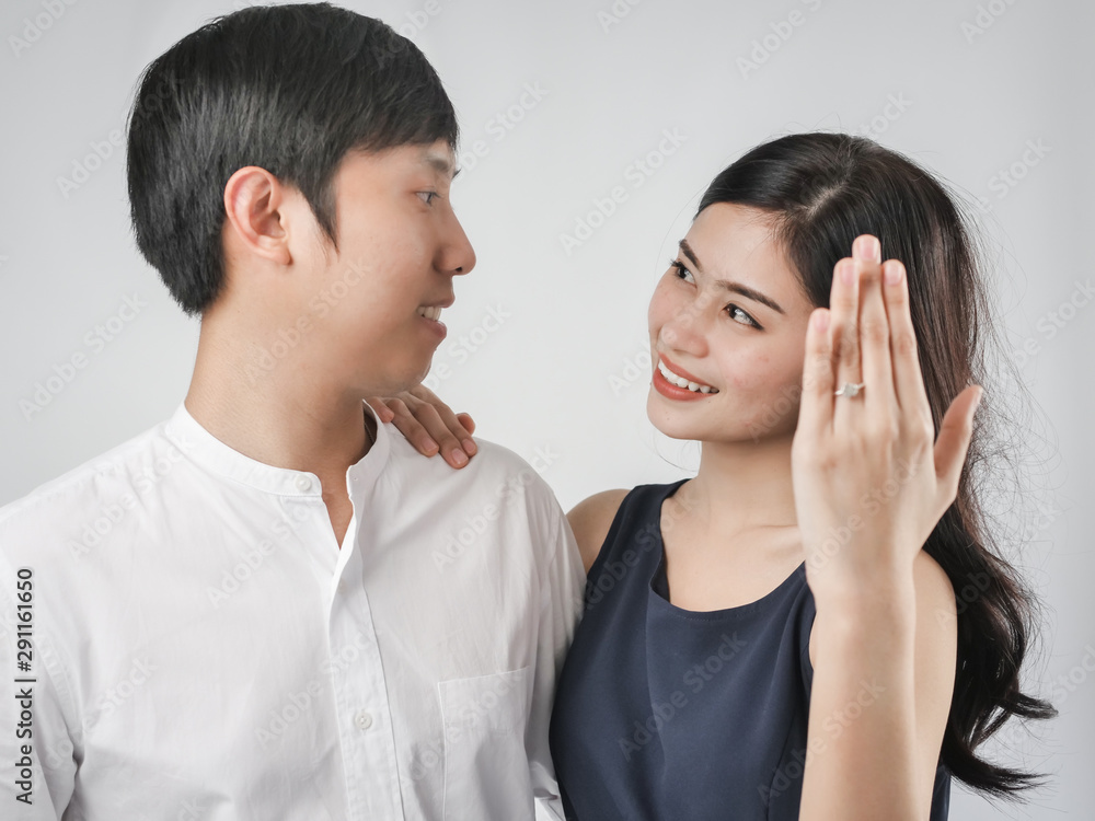 Happy woman showing engagement ring after proposal while is cuddling her boyfriend. Happy woman showing engagement ring after proposal while is cuddling her boyfriend.