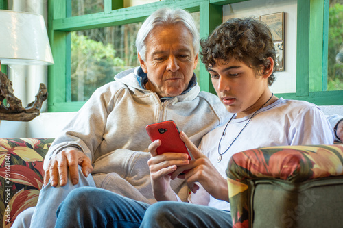 Father and teenage son with mobile phone fun social network